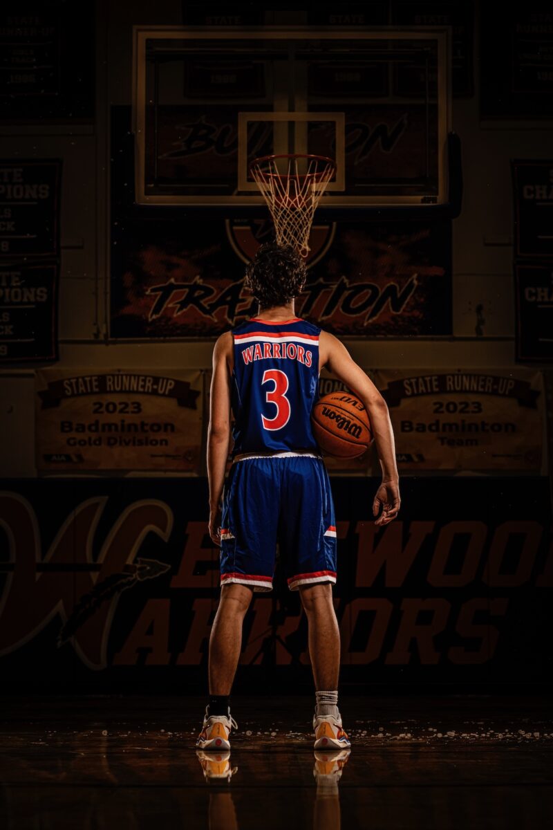 Basketball player standing with his back to the camera holding a ball wearing jersey number three