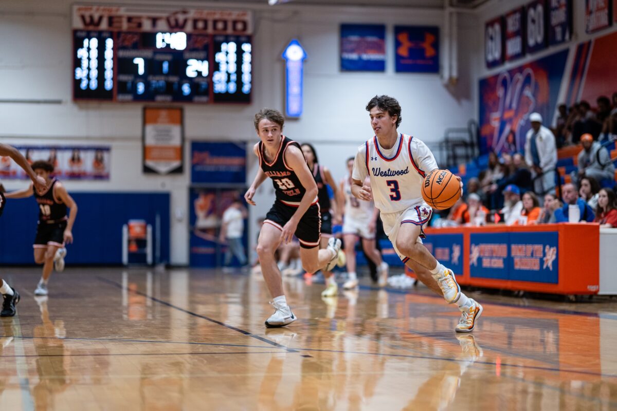 Basketball player wearing jersey number three dribbling past a defender